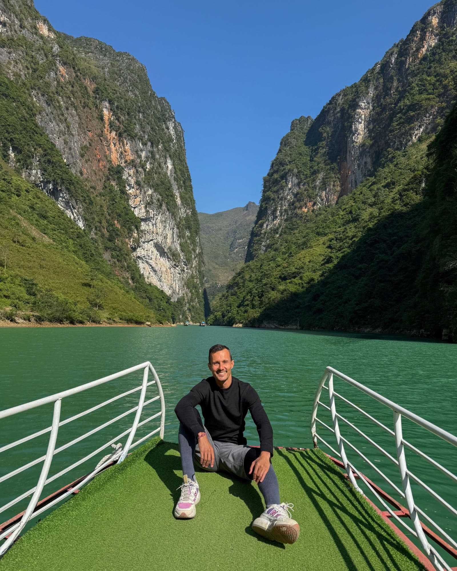 A small boat on the emerald Nho Que River inside Tu San Canyon